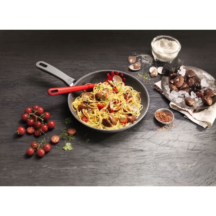 fry pan filled with pasta and veggies on a black wooden table.