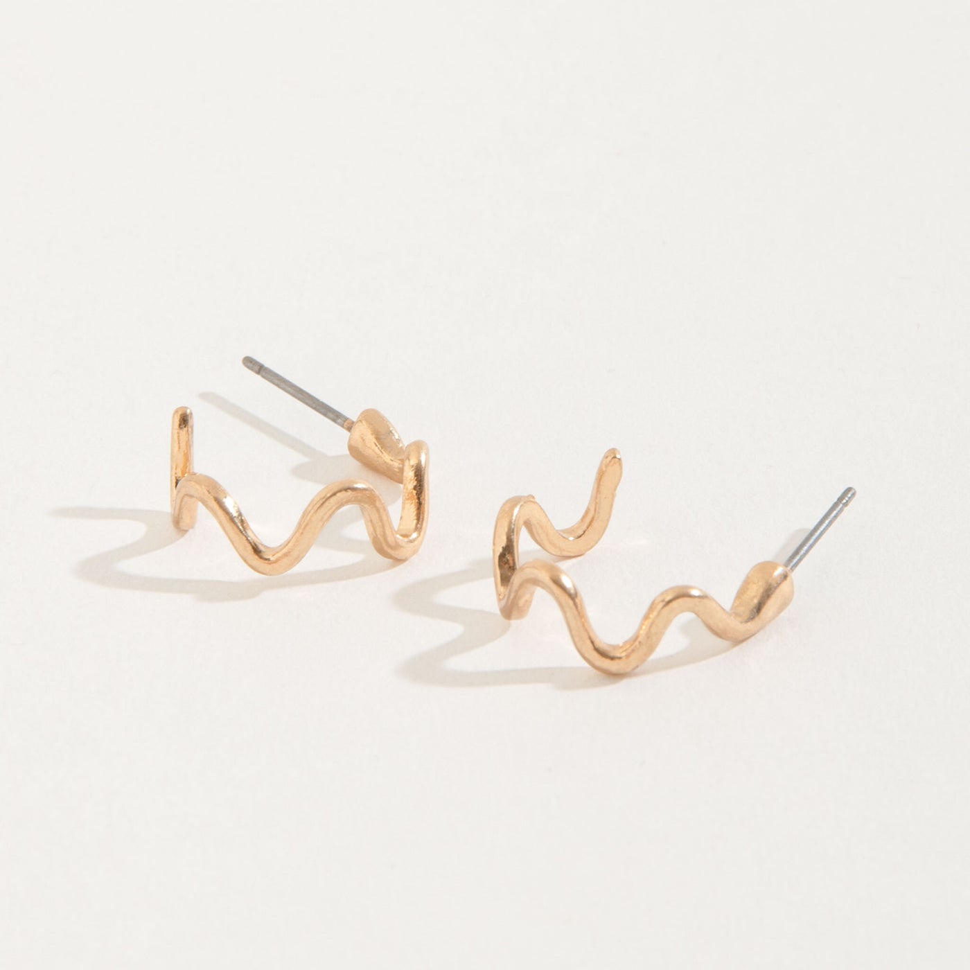 gold wiggle hoop stud earrings on a white background
