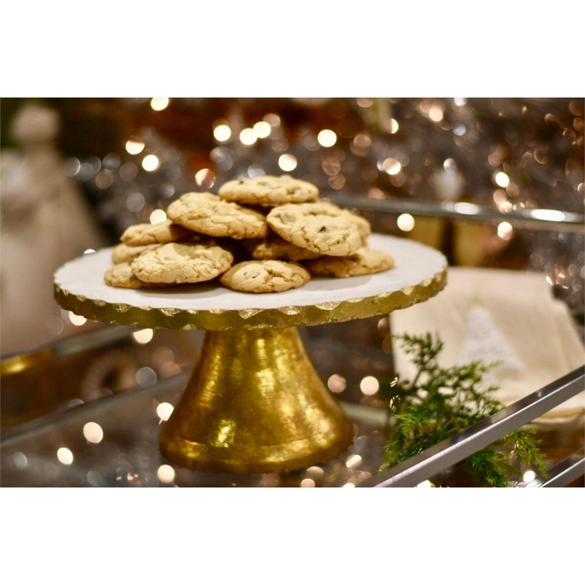 marble and gold cake stand set on a bar cart and filled with cookies.