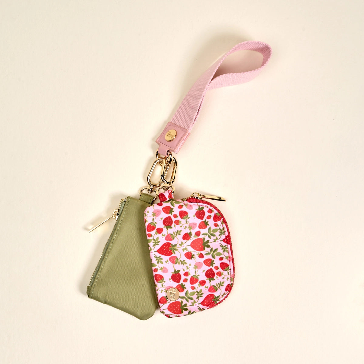 Two keychains, one green and one with strawberry pattern, on a beige background.