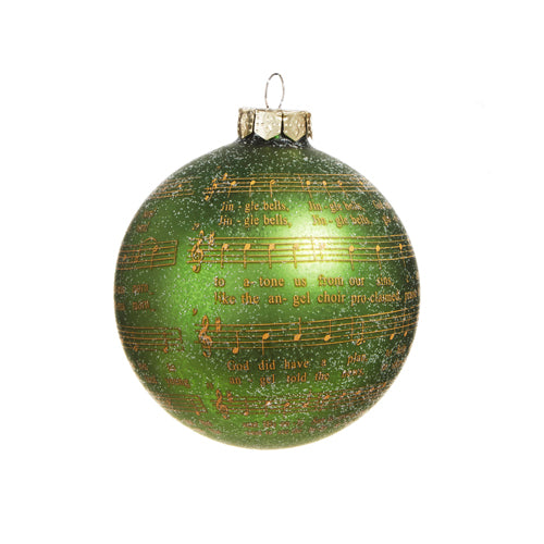 glitter green ball ornament with gold sheet music wrapped around against a white background