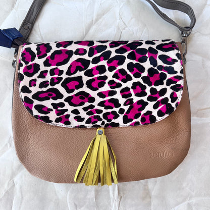 rounded brown purse with black and pink cheetah print flap, yellow tassel, and grey strap.