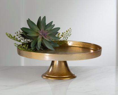 small round gold pedestal with greenery on it