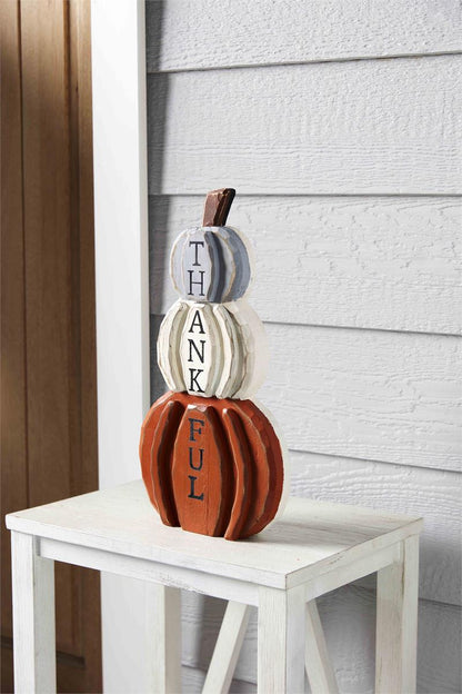 pumpkin side of the reversible plaque displayed on a whitewashed table next to a door