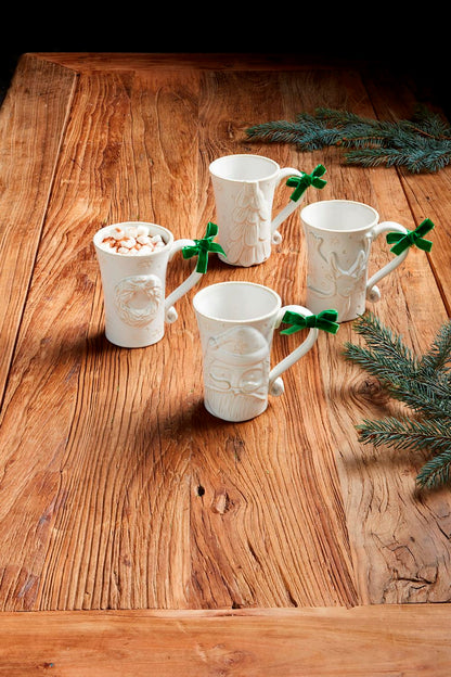 4 styles of White Christmas Mugs arranged on a wooden table with greenery.