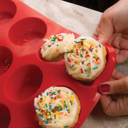 hands removing cupcake from pan showing silicon flexibility