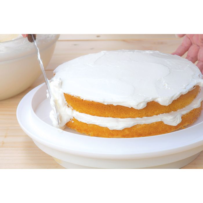 hands putting icing onto layered cake