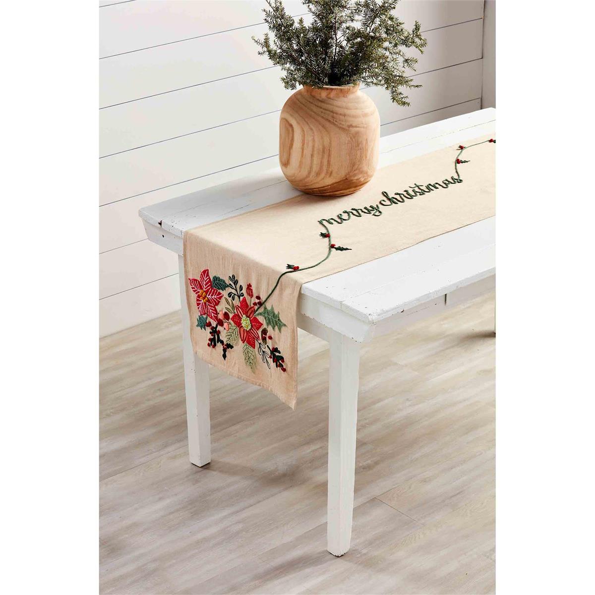 merry christmas poinsettia table runner displayed on a white dining table with a large wooden vase filled with pine sprigs