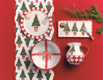quilted tree table runner on a red background with dishes and greenery