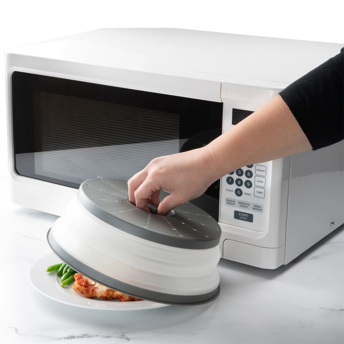 person taking Collapsible Microwave Food Cover off a plate of food