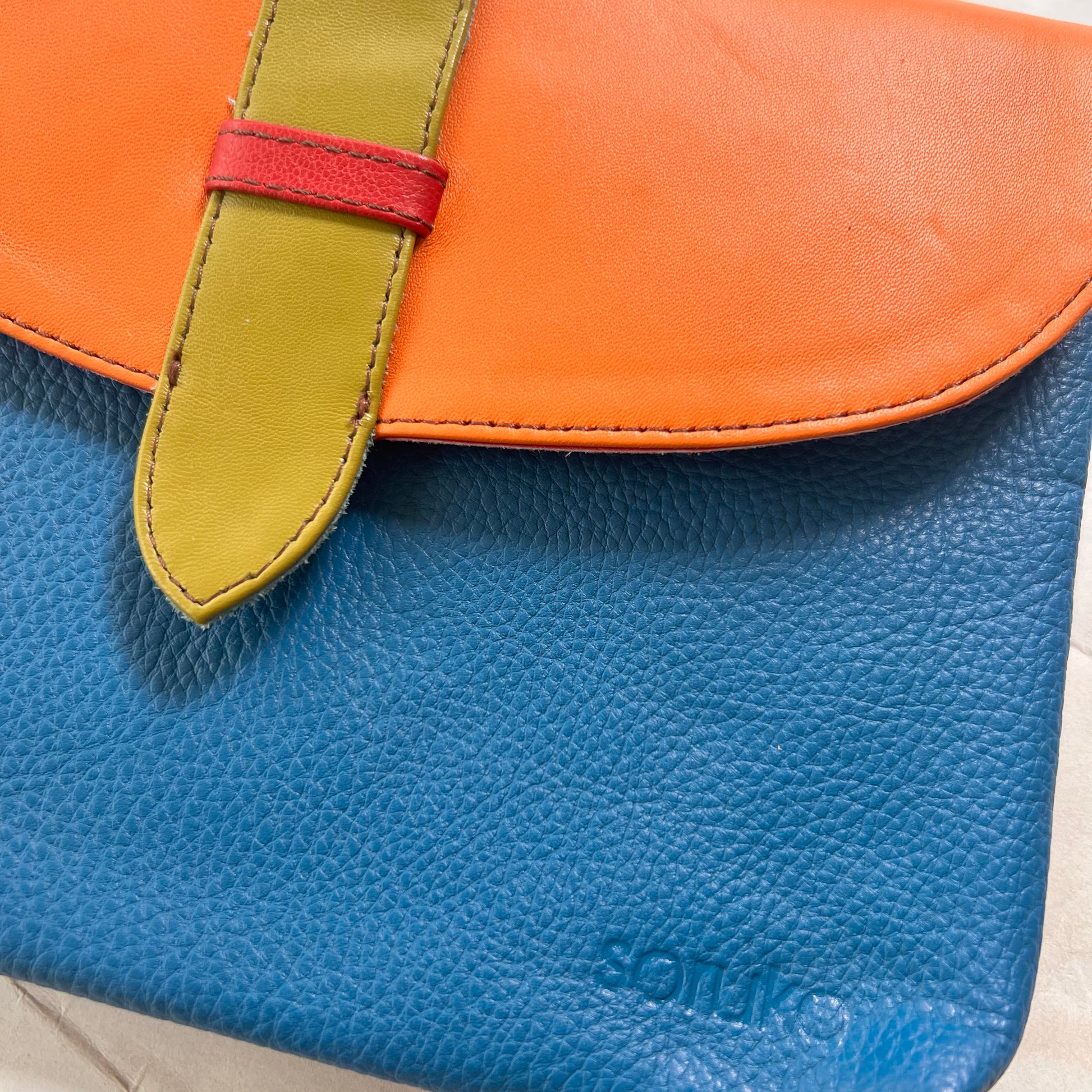 close-up of blue saddle bag with orange flap and lime tab.