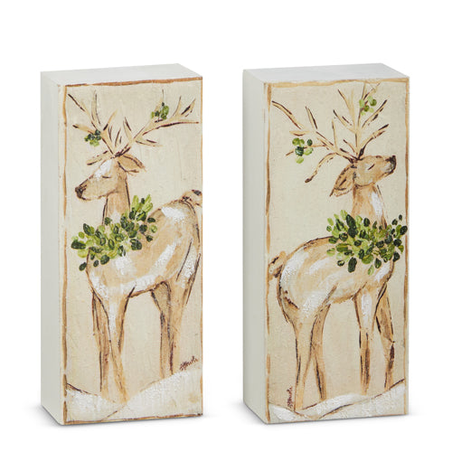 2 wooden blocks painted with a deer wearing a greenery wreath around its neck.