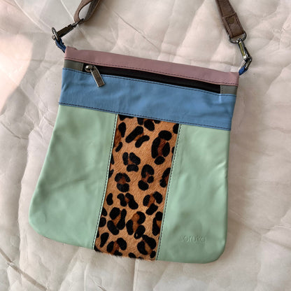 seafoam greta bag with animal print block in the center with blue stripe and zipper across the top.