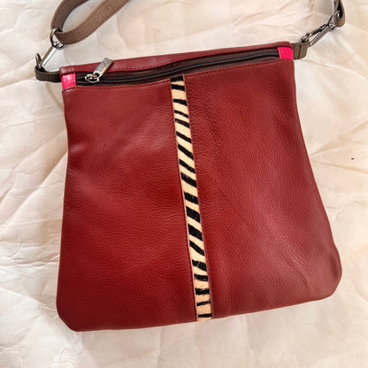 maroon greta bag with animal print stripe down the center and zipper at the top.