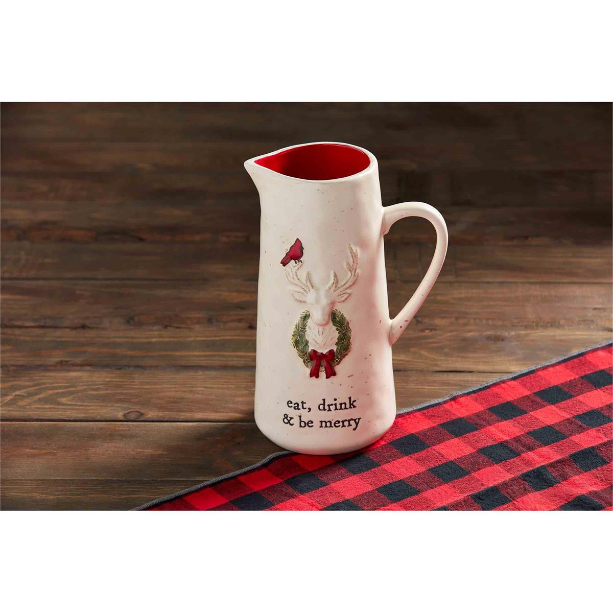 eat, drink and be merry deer pitcher sitting on a dark stained wood slat table with a buffalo checked runner