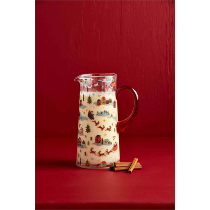 christmas village pitcher filled with milk and displayed against a red background next to multiple cinnamon sticks