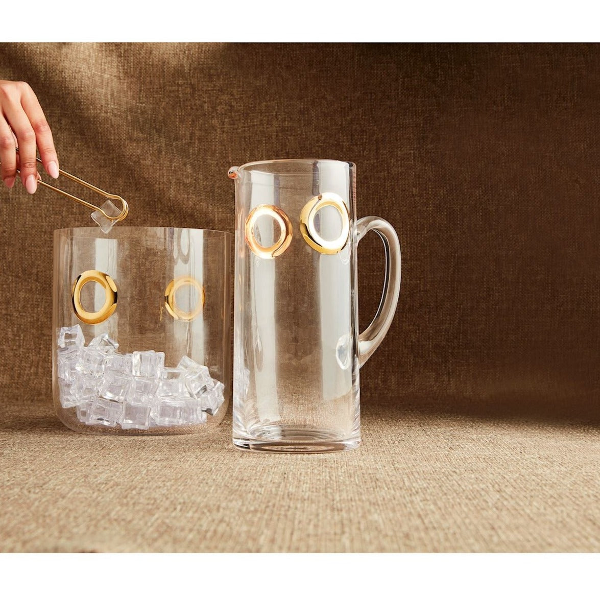 glass pitcher with gold circles around the top set on a couter with an ice bucket behind it.