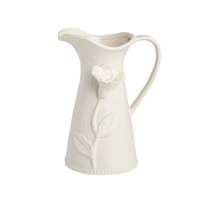 White ceramic pitcher with floral design on a white background