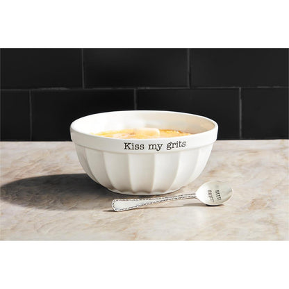 grits bowl filled with hot grits set on a countertop with spoon next to it.