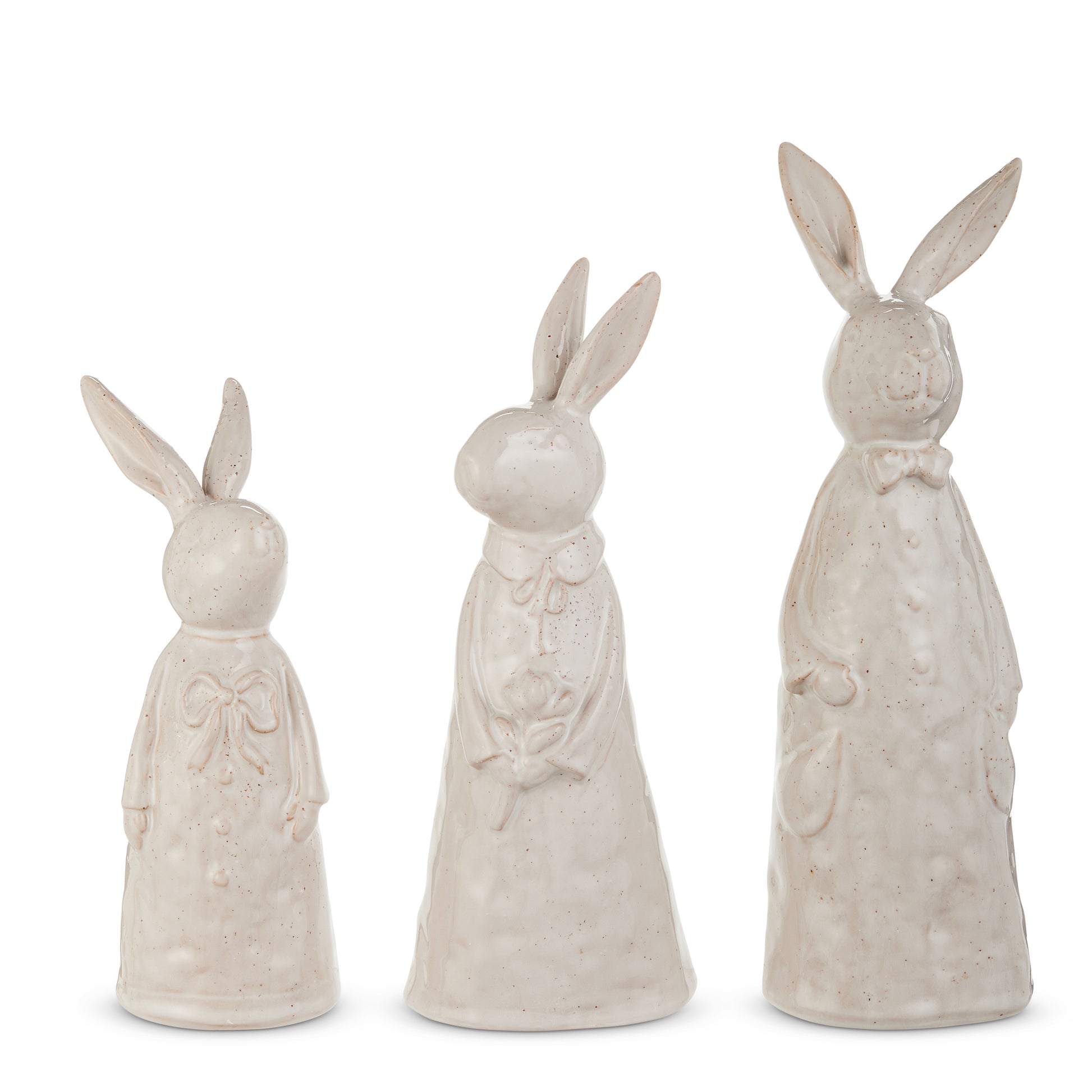 3 cream colored ceramic textured rabbits in frocks stainding against a white background