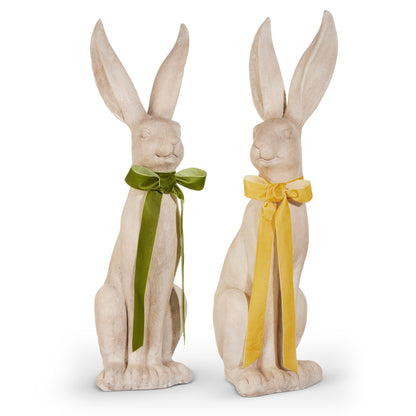 2 concrete looking rabbit figurines with a green bow on one and a yellow bow on the other