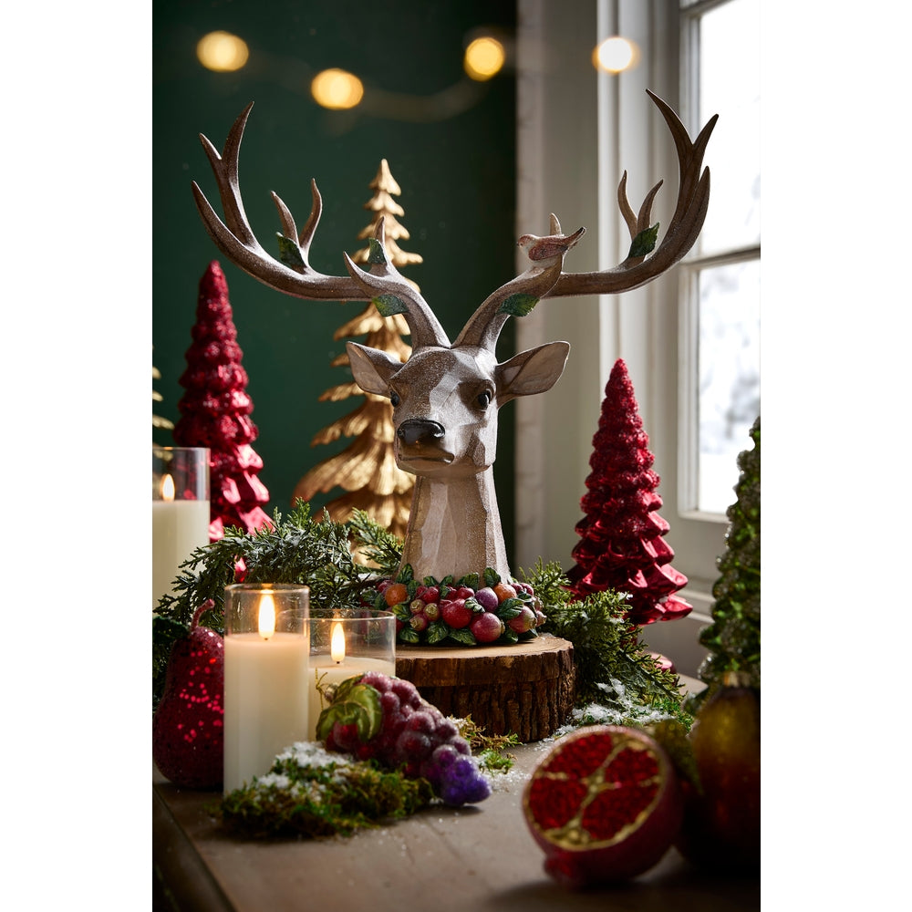 Enchanted Deer Bust on a decorated table surrounded by tree figurines and greenery
