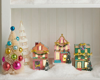 3 light up multicolor house ornaments on a decorated shelf
