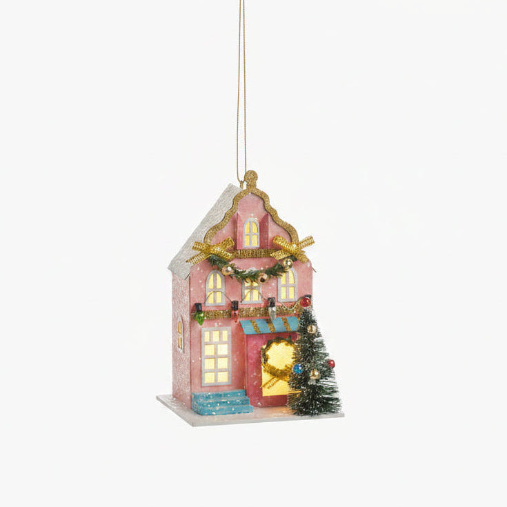 pink house ornament decorated for christmas with lights in the  windows