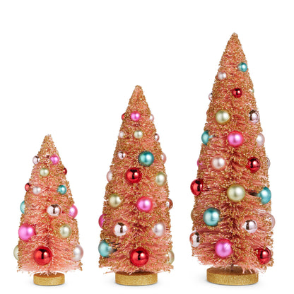 3 pink bottle brush trees dusted with gold glitter and embellished with colorful ornaments on a white background