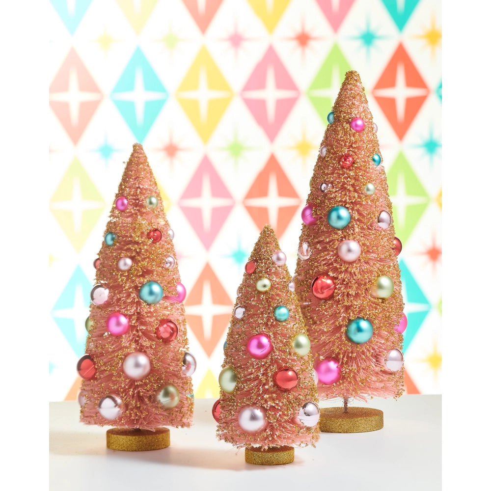 Three pink Christmas trees with pearl-like baubles in pastel colors, displayed on a white surface against a retro pastel diamond-patterned background.