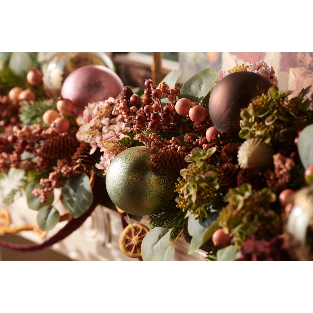 close-up of christmas garland filled with ornaments, greenery and floral elements in sage green and blush hues