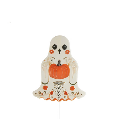 A decorative ghost-shaped yard stack with black eyes, orange floral accents, and holding an orange punpkin