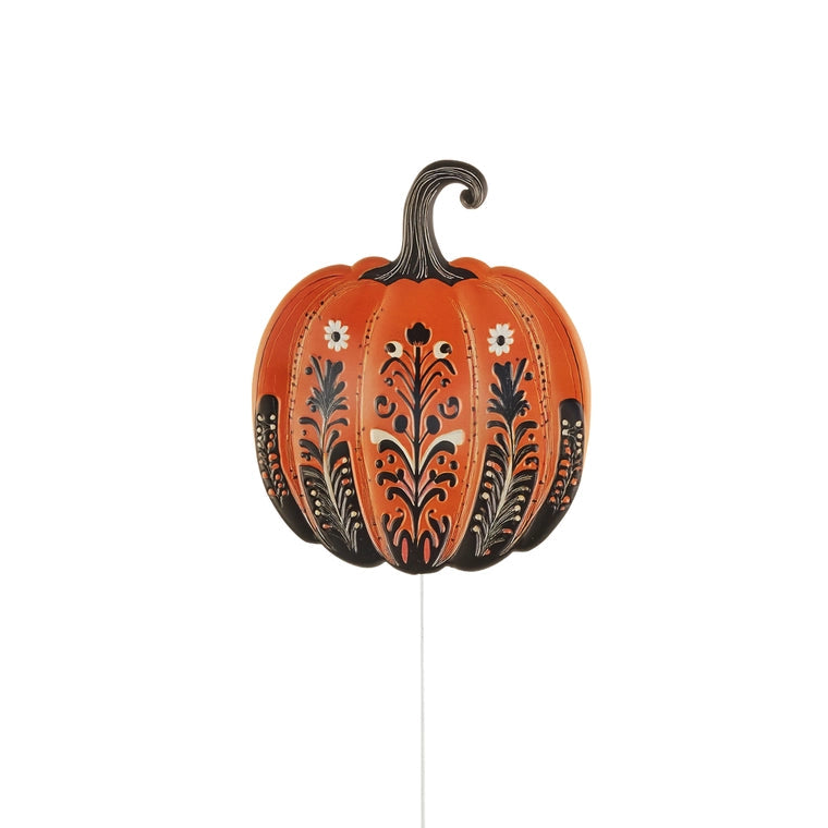 An orange decorative pumpkin yard stake with black and white floral patterns and a dark stem, shown against a plain white background.