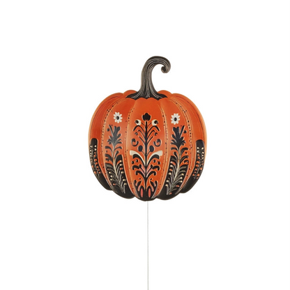 An orange decorative pumpkin yard stake with black and white floral patterns and a dark stem, shown against a plain white background.