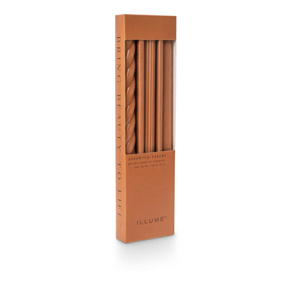 three assorted orange taper candles in their packaging
