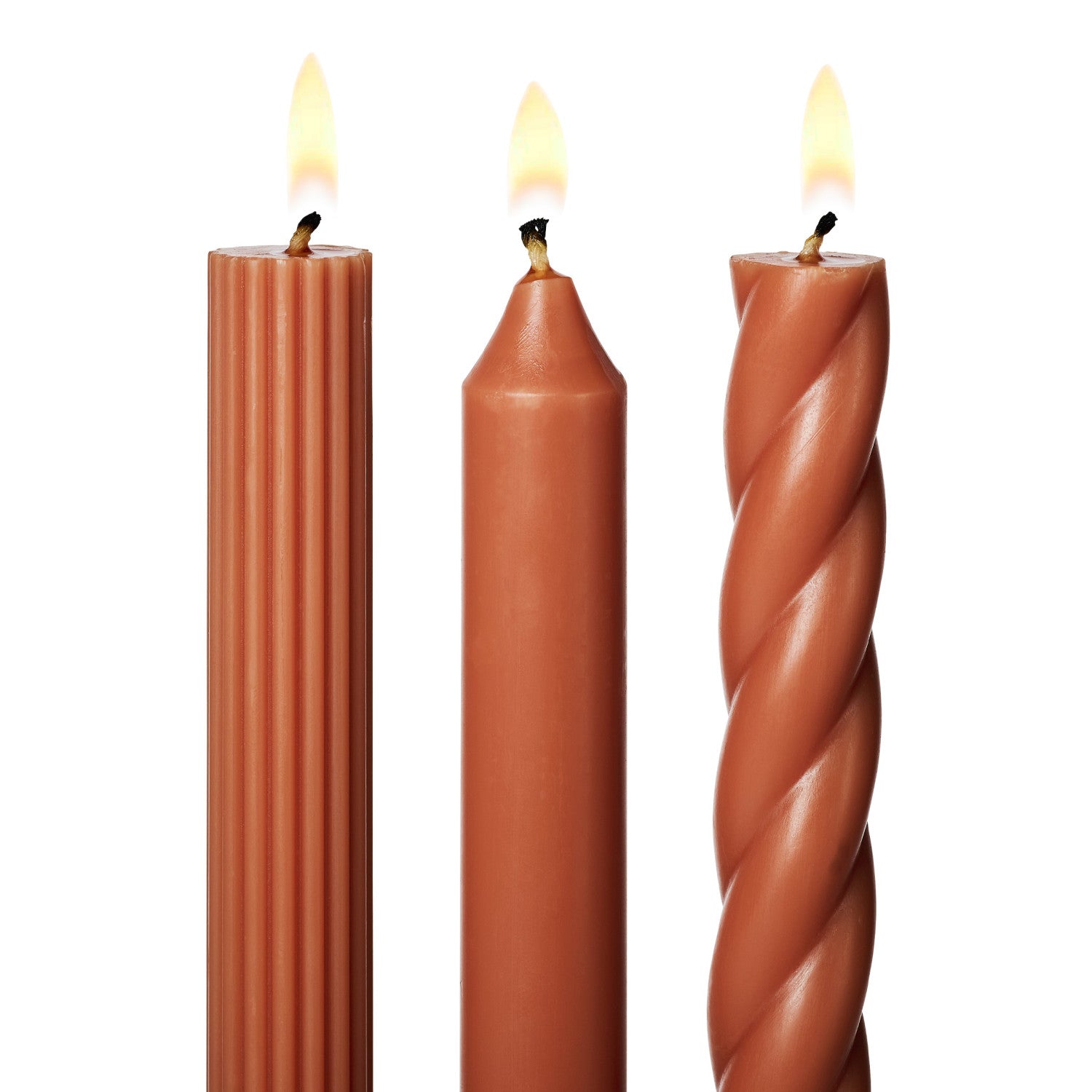 three lit assorted orange taper candles on a white background
