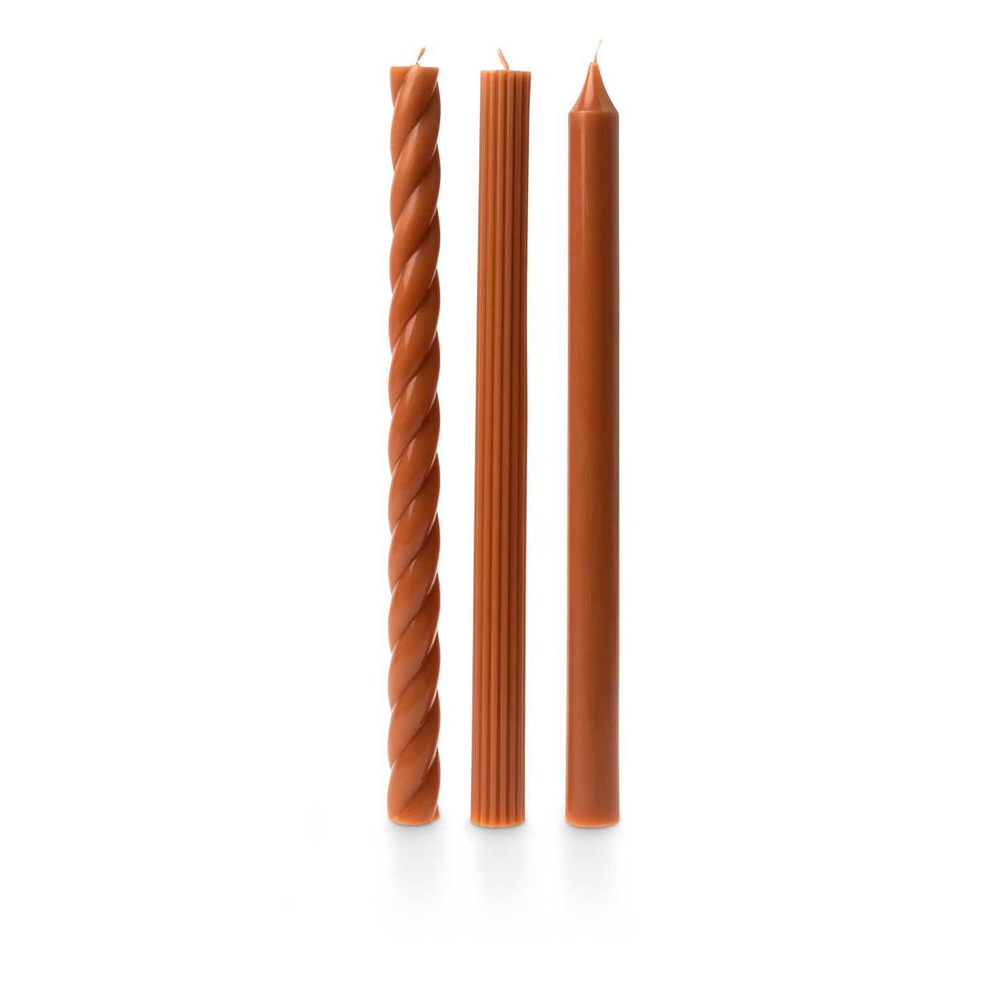 three assorted orange taper candles on a white background