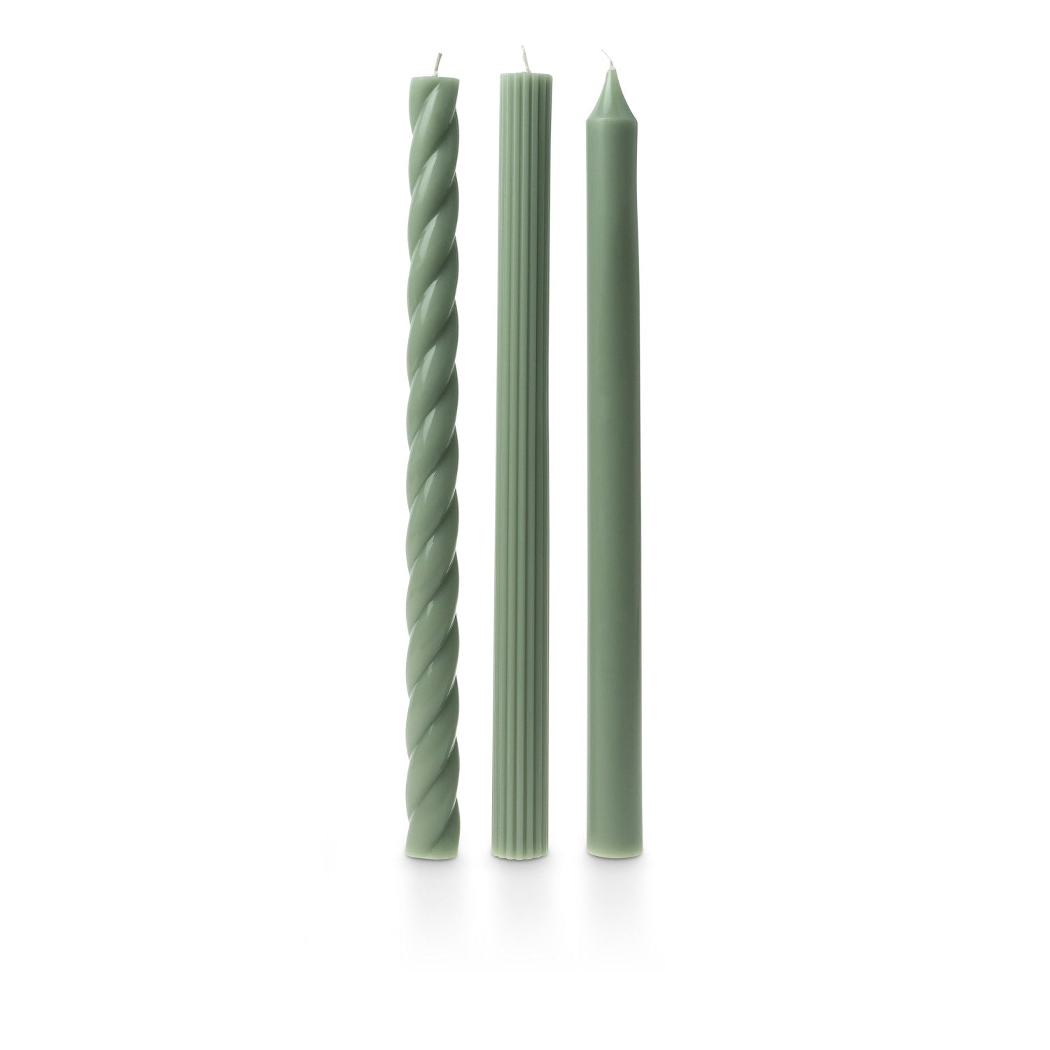 three assorted green taper candles on a white background