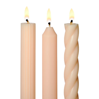 three lit assorted blush taper candles on a white background