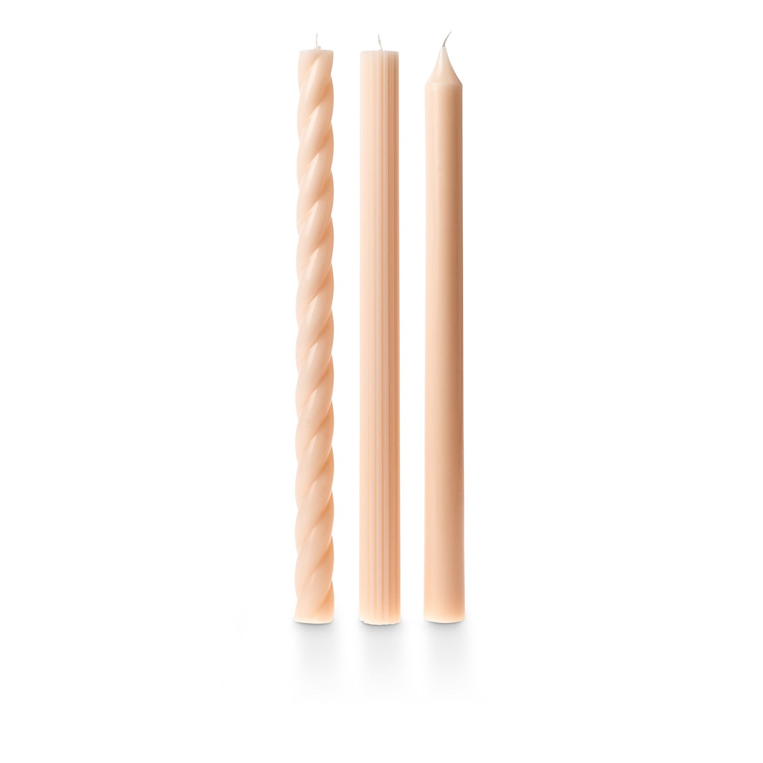 three assorted blush taper candles on a white background