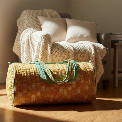 Yellow floral pattern bag with green handles set next to a cozy chair