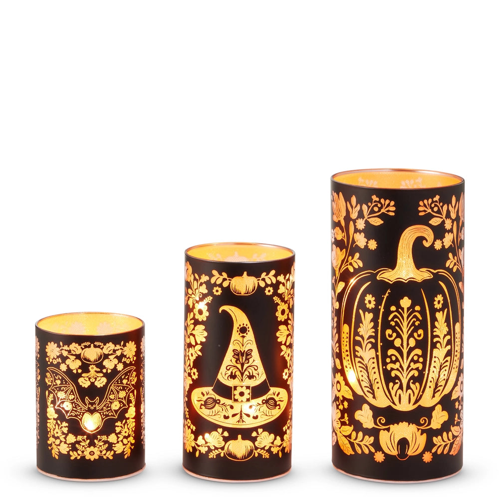 Three sizes of black and orange glass cylinders with etched floral Halloween design on and illuminated from the inside