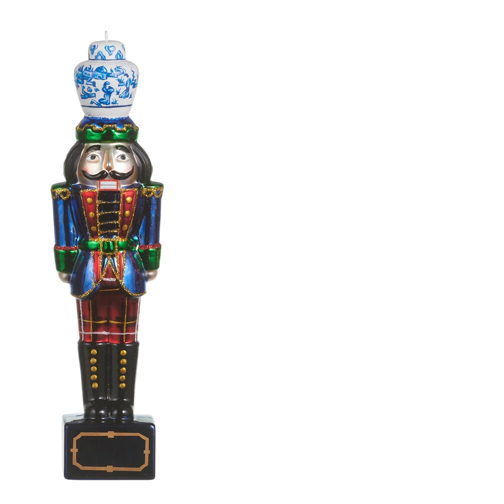 glass nutcracker ornament with wearing blue coat and red plaid pants with a blue and white ginger jar on its head