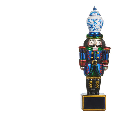 glass nutcracker ornament with wearing blue coat and green pants with a blue and white ginger jar on its head
