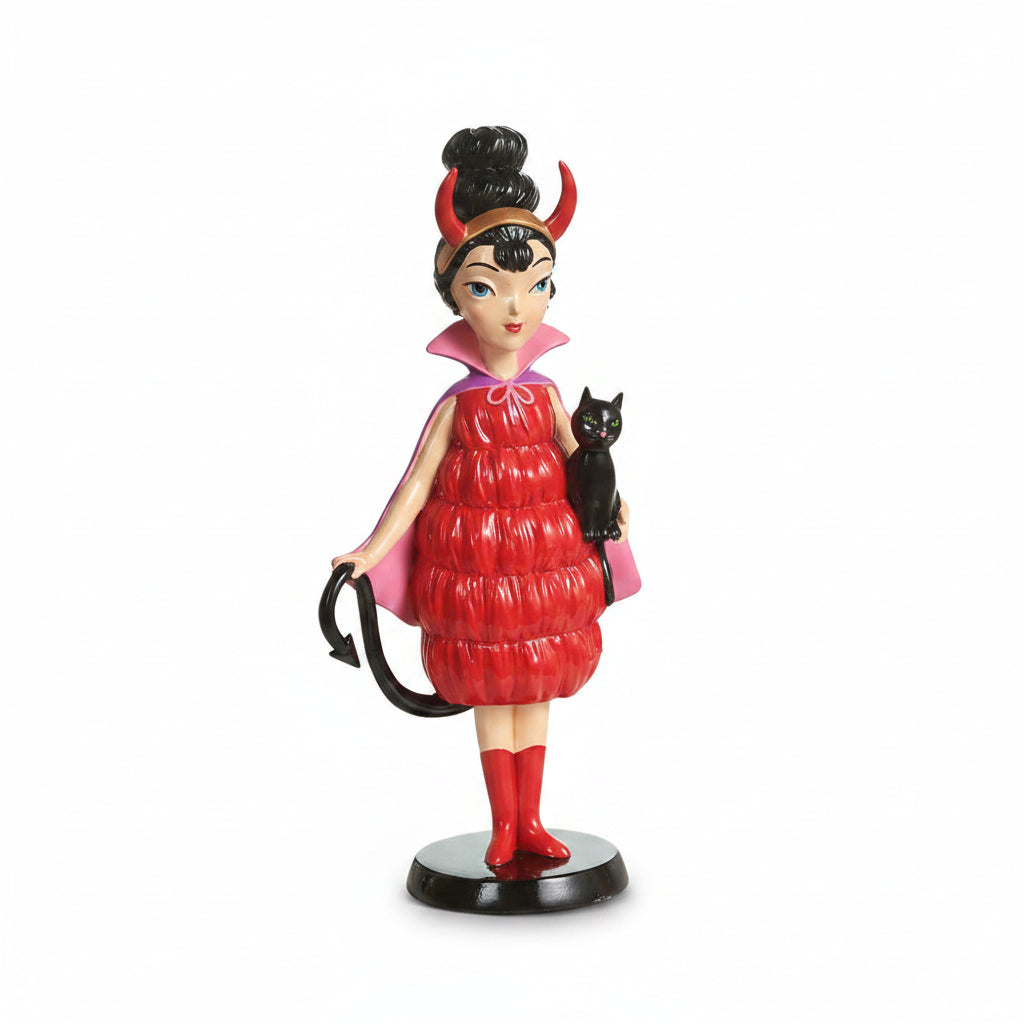 witch figurine wearing a vintage style red dress and pink cape. she is holding a black cat and a tail and has devil hon on her head