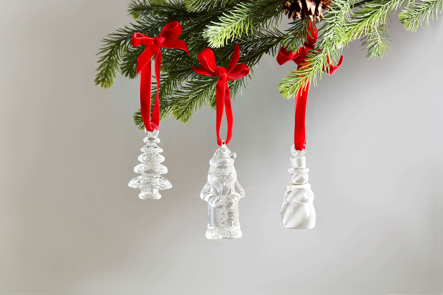 3 styles of glass ornaments hanging from a sprig of greenery.