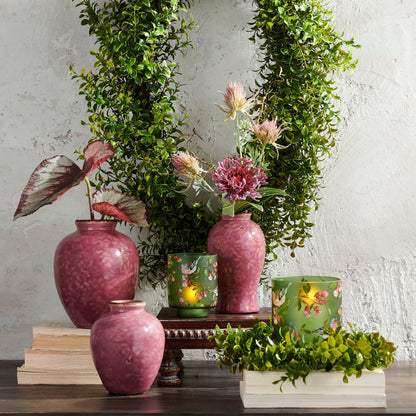 bird floral pattern containers arranged with pink vases and greenery against a plaster wall