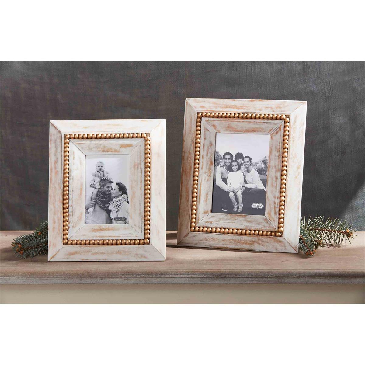 both sizes of gold bead frames displayed on a light wood narrow table against a dark gray wall