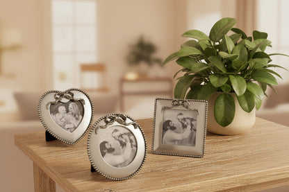 Three decorative photo frames on a wooden surface with a plant in the background