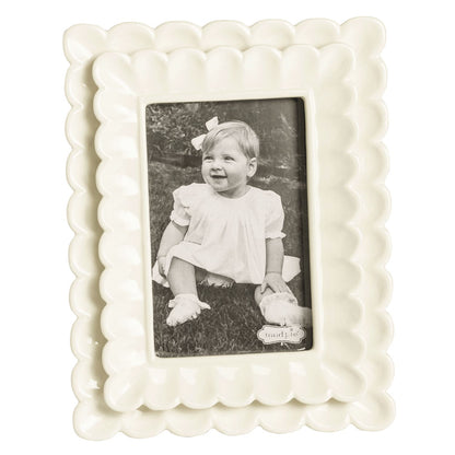 small White scalloped photo frame with a black and white photo of a child inside